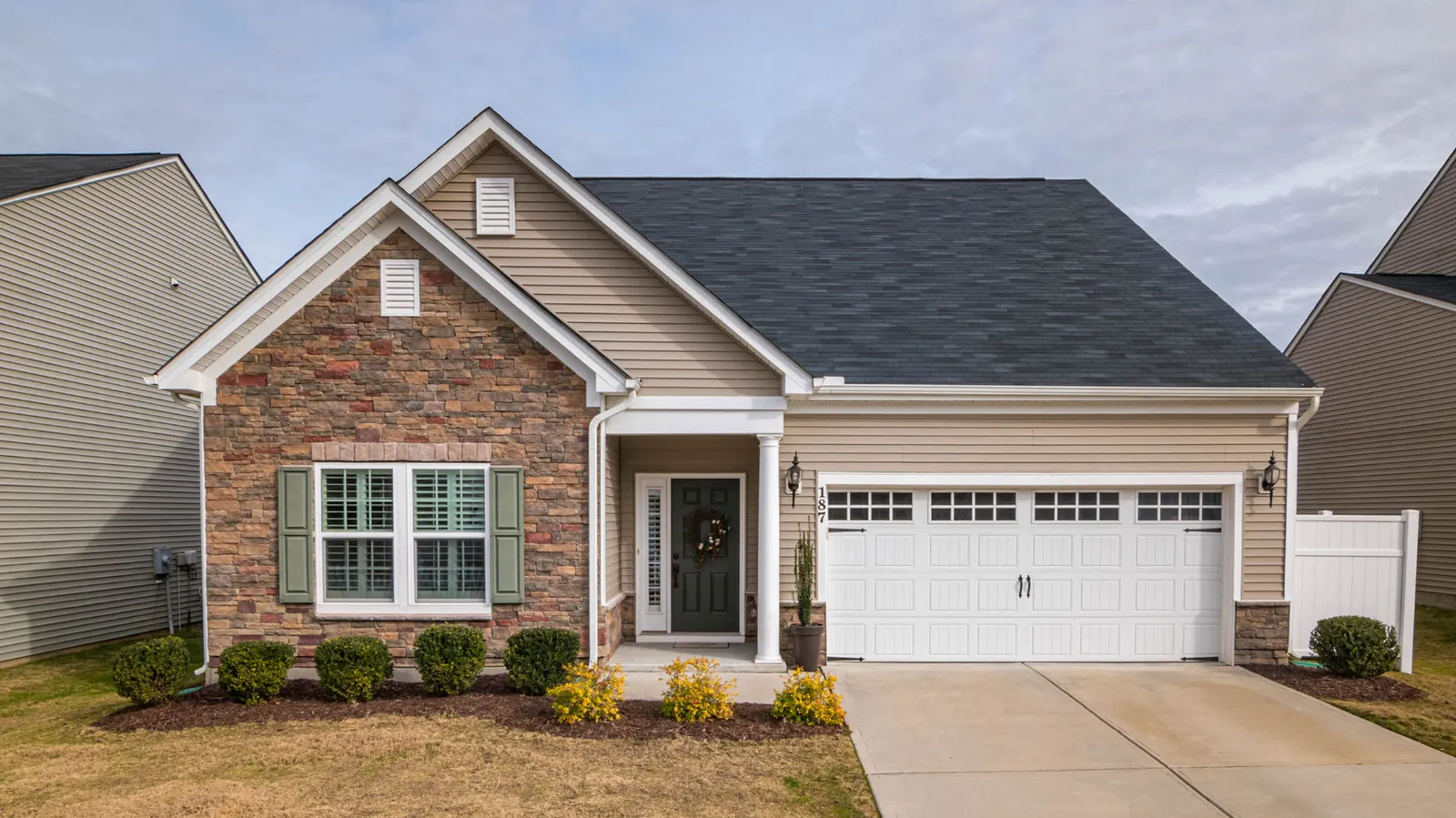 Stone accented ranch home beneath a dark gray asphalt shingle roof
