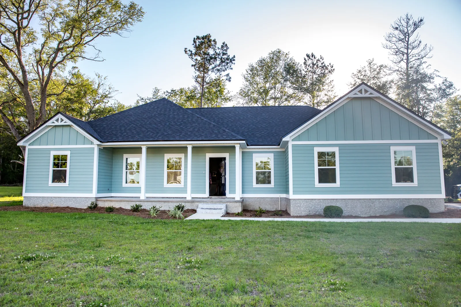 Front porch on a light blue home under a dark asphalt shingle roof