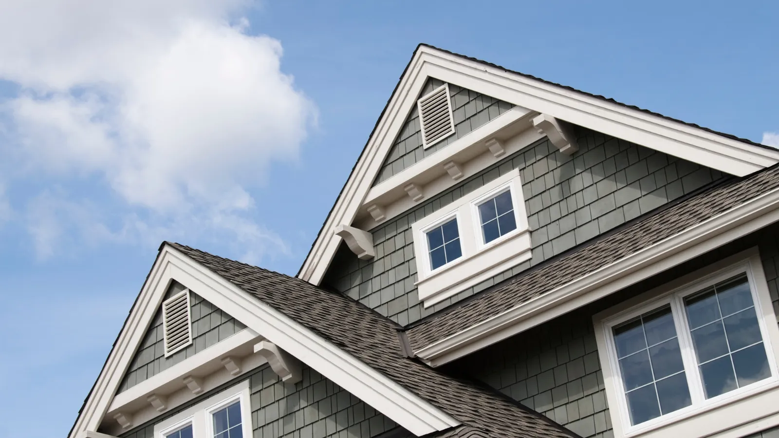 White trimmed house gables rising above a brown shingle roof